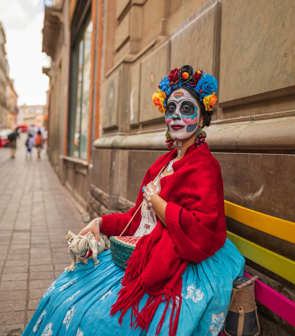a woman in a traditional costume on the street during the fall Día de los Muertos