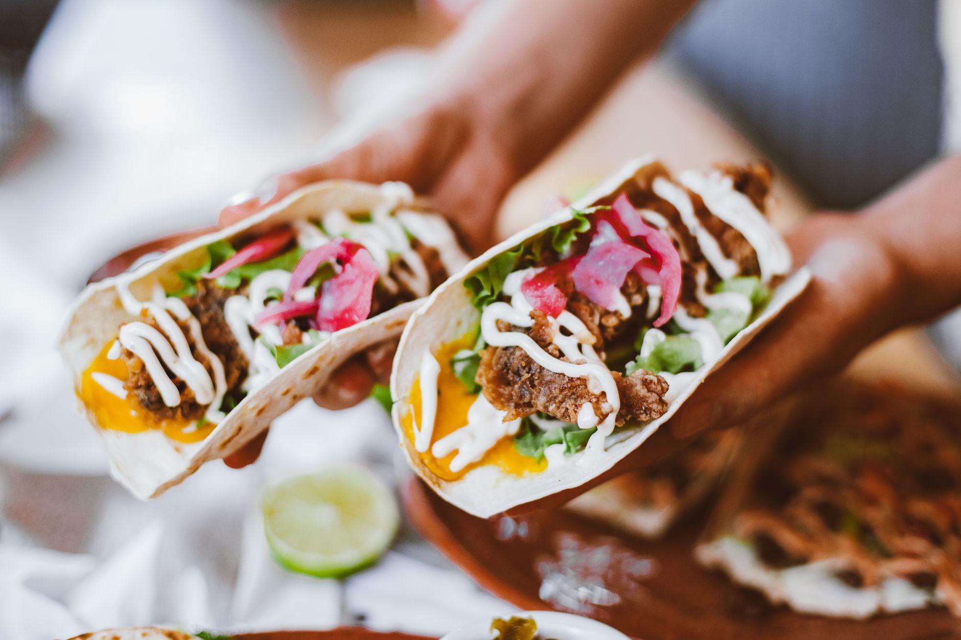 close up of hands holding stuffed tortillas